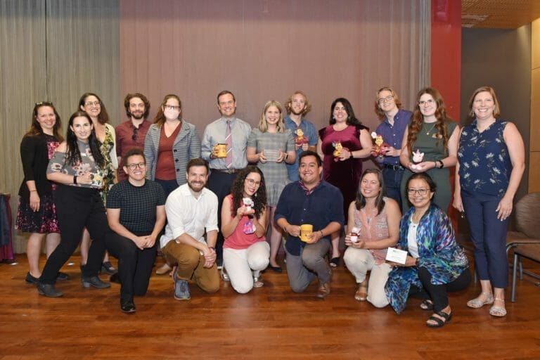A group of people holding presents while smiling at the camera