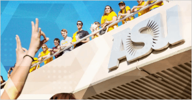 Students on the bridge looking down while majority is wearing golden shirts and a person from the bottom is showing sun devil sign with hands
