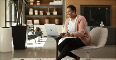 A person is typing on a laptop while smiling and sitting