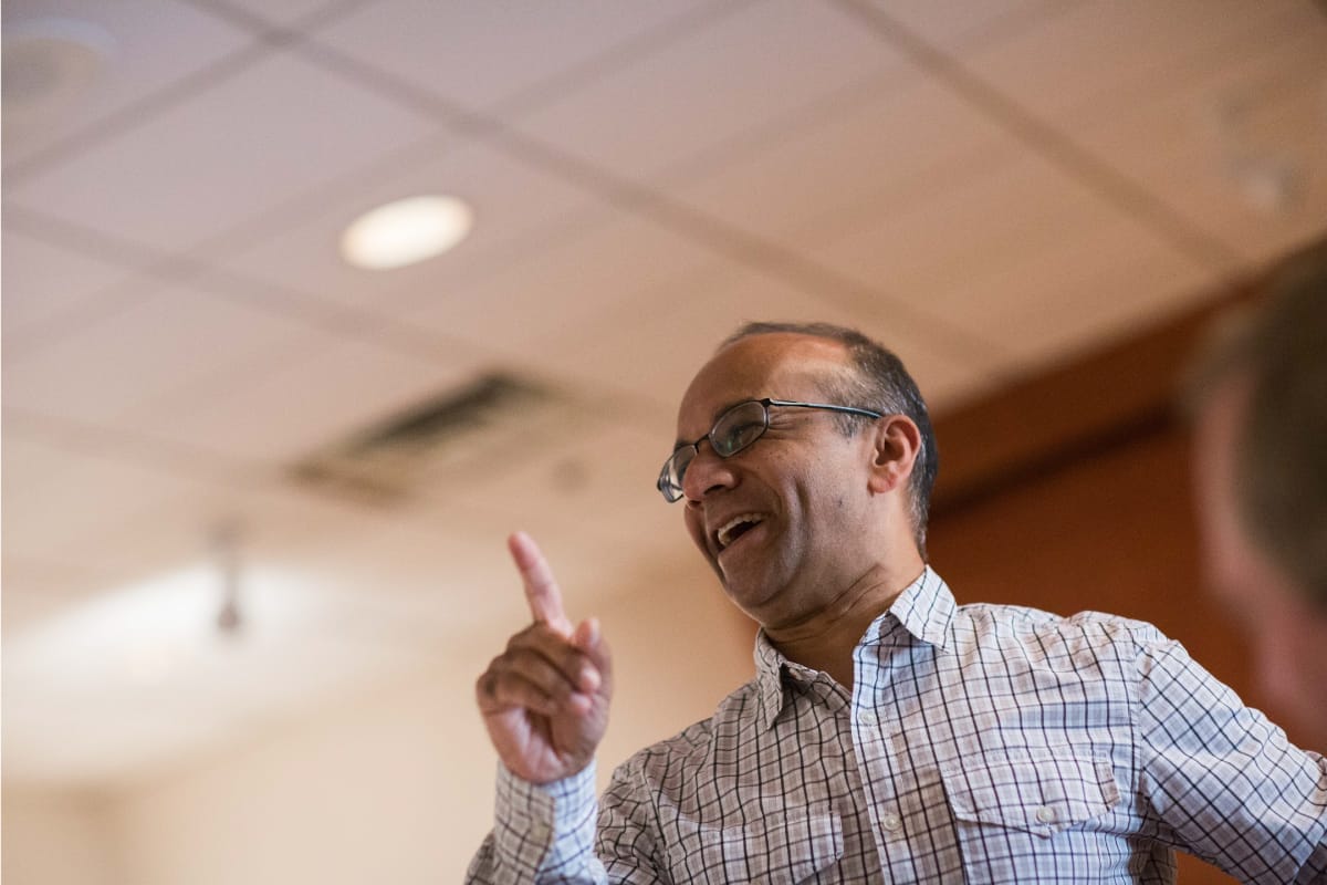 A person standing while pointing finger to above direction and smiling
