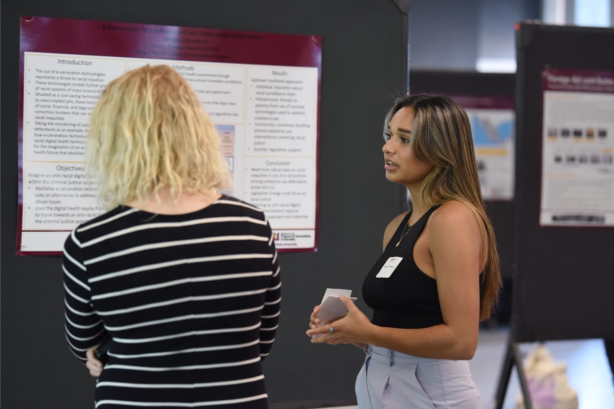 Two people are talking to each other while standing in front of a poster