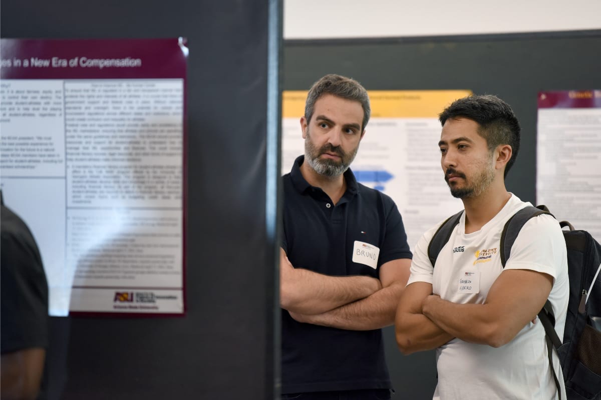 Two people are looking at the poster in a conference