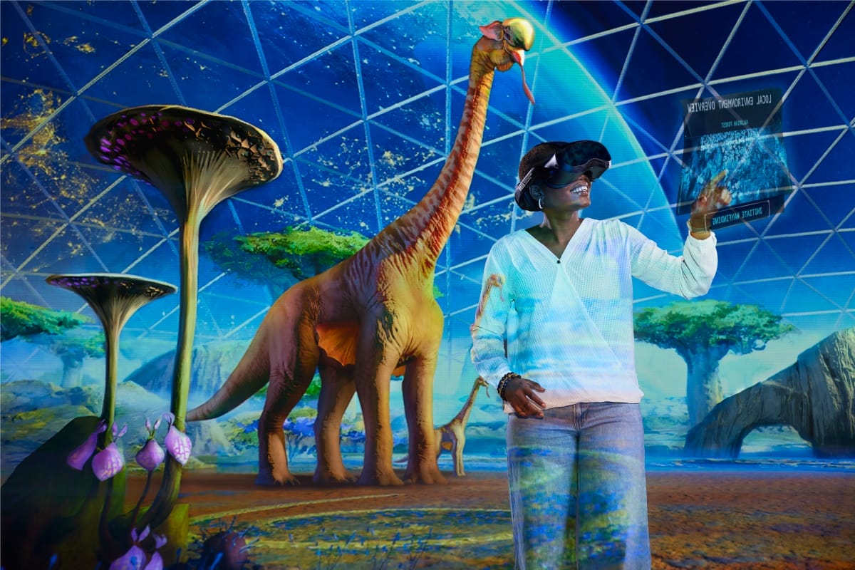 A person wearing ER headsets and pointing at a graph while there are dinosaurs in the background