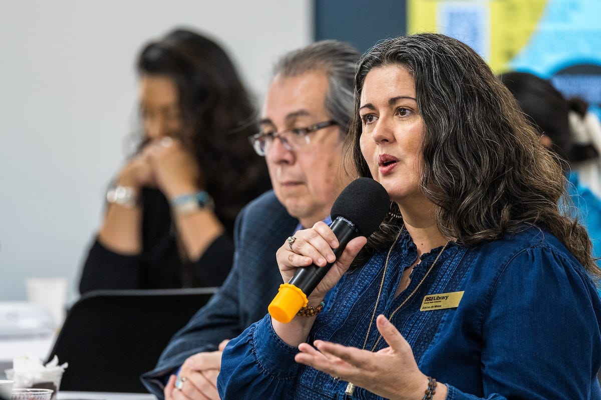 A person who is holding a mic delivering speech to people in the room